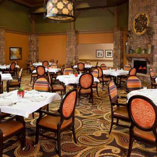 An elegant restaurant dining room with neatly arranged tables and chairs, featuring a warm and inviting atmosphere.