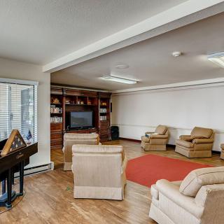 A cozy living room with multiple armchairs, a television, and built-in bookshelves.