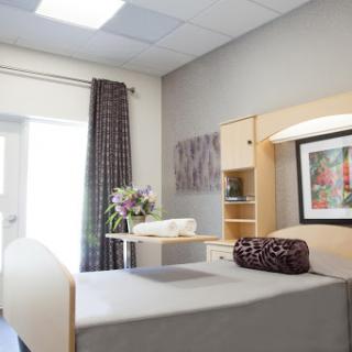 A well-furnished hospital patient room featuring a bed, bedside table, and decorative elements.