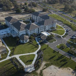 Aerial view of a large multi-story building surrounded by landscaped greenery and pathways.