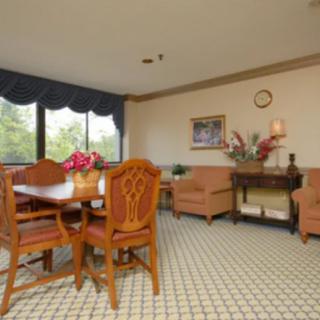 A cozy living room with a dining area, featuring classic furniture and large windows.