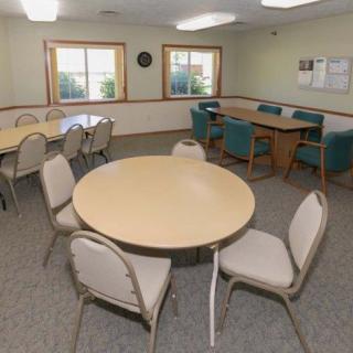 A multipurpose office meeting room with tables and chairs arranged for group discussions.