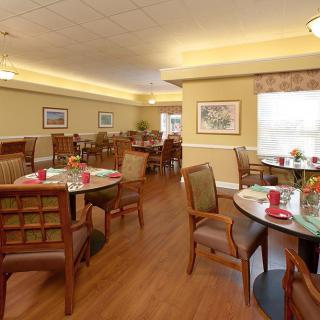 A warmly lit dining room with neatly arranged tables and chairs.
