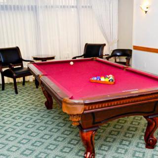 A well-furnished game room featuring a red pool table and comfortable seating.