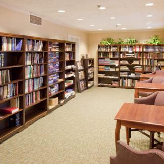 A cozy library with bookshelves lining the walls and reading tables in the center.