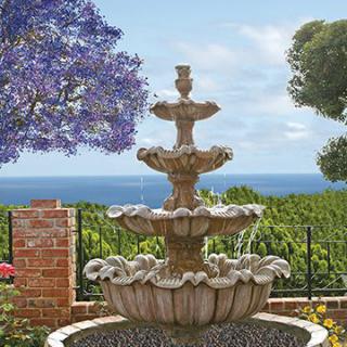 A beautiful three-tiered fountain in a garden with a stunning sea view.