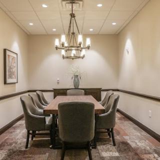 A well-lit meeting room featuring a large conference table and comfortable chairs, suitable for discussions and presentations.