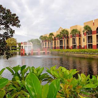 A scenic view of a resort featuring a water fountain, lush greenery, and modern architecture.