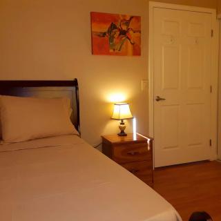 A cozy bedroom with a bed, nightstand, and lamp under warm lighting.