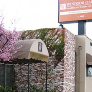 The exterior of a building with a brick wall, ivy, and pink flowering tree, featuring an entrance with an awning and a sign above.