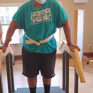 A patient undergoing physical therapy while using parallel bars for support.