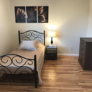 A minimalist bedroom with a single bed, bedside lamp, and a dresser.