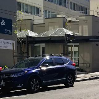 A blue SUV parked on the street in front of a building.