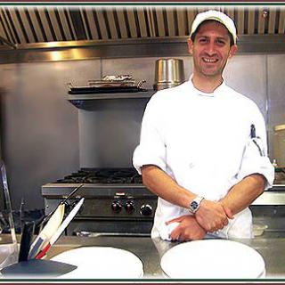 A chef smiling in a restaurant kitchen.