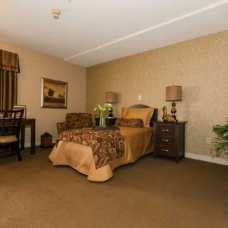 A cozy bedroom with elegant decor, featuring a bed, side tables with lamps, and a seating area.