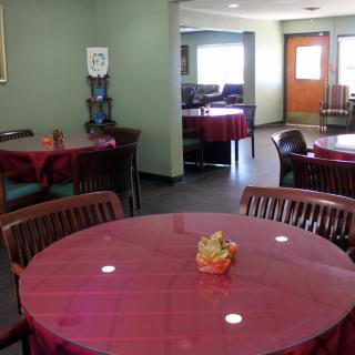 An empty dining area with tables covered in red tablecloths.
