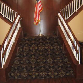 A carpeted staircase with an American flag at the top.