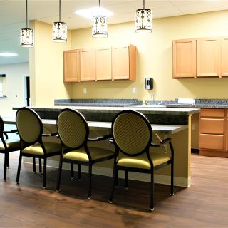 A modern kitchen interior featuring a countertop with chairs, wooden cabinets, and pendant lighting.