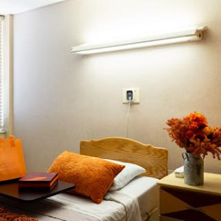 A cozy and well-lit bedroom featuring orange accents and floral decor.