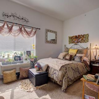 A cozy bedroom with elegant decor, featuring a bed surrounded by soft pillows and a sunlit window.