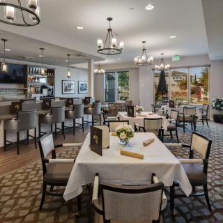 A modern restaurant dining area with neatly arranged tables and a stylish bar.