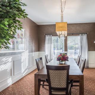 A well-lit dining room featuring a wooden table, chairs, and a chandelier.