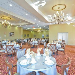 An elegant dining room with chandeliers and neatly set tables.