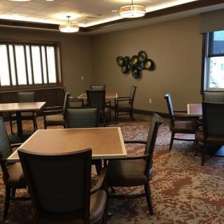 A cozy dining area with multiple tables and chairs, featuring a patterned carpet and warm lighting.