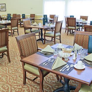 A neatly arranged dining room with set tables and chairs, ready for guests.