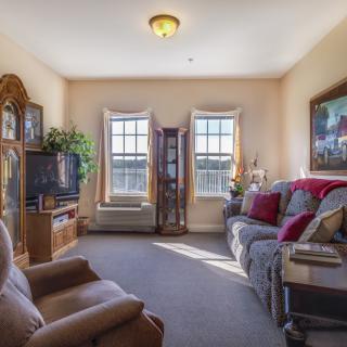 A cozy living room with comfortable seating, a TV, and large windows letting in natural light.