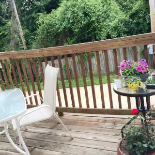 A cozy deck area with outdoor furniture and flowering plants.
