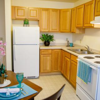 A cozy kitchen with wooden cabinets, white appliances, and a small dining setup.