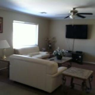 A cozy living room with a sofa, television, and ceiling fan.