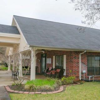 A suburban brick house with a covered porch and well-maintained yard.