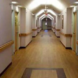 A well-lit hospital corridor with wooden flooring.