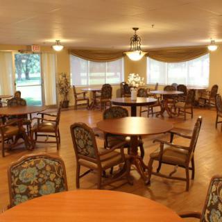 A cozy dining room with multiple tables and chairs, featuring wooden furniture and a warm ambiance.