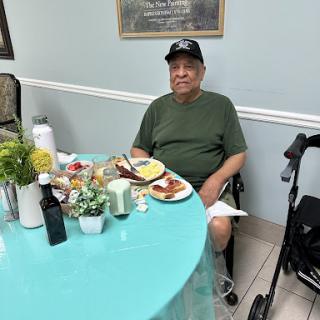 An elderly man enjoying a meal at a dining table.