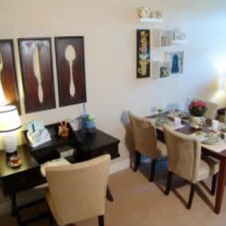 A cozy dining room setup featuring a rectangular table with cushioned chairs and artistic wall decor.