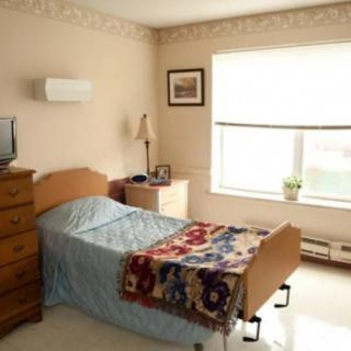 A cozy bedroom with a single bed, a colorful quilt, and natural light coming through the window.