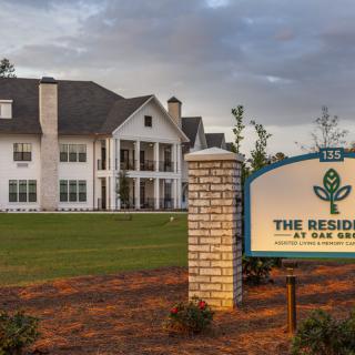 A luxurious residence with a large lawn and a prominent entrance sign.