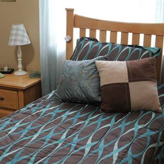A neatly made bed with patterned bedding and decorative pillows, next to a nightstand with a lamp.