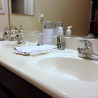 A tidy bathroom sink area with faucets, mirrors, and neatly placed towels.