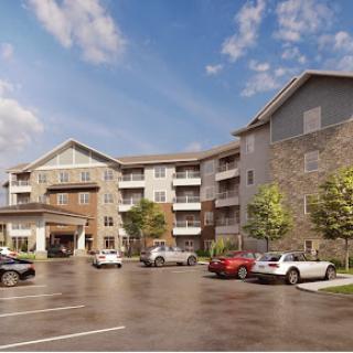 A modern apartment building featuring a spacious parking area and surrounded by greenery.