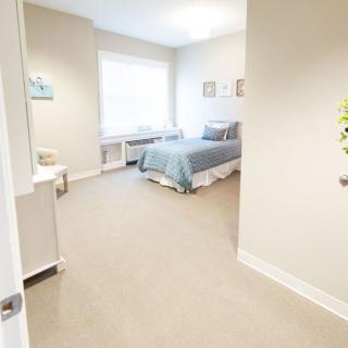 A bright and minimalist bedroom with a neatly made bed and a large window letting in natural light.
