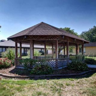 A scenic view of a wooden gazebo surrounded by greenery in a garden setting.