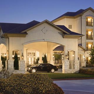 An elegant hotel entrance with a car parked under the porte-cochre during the evening.