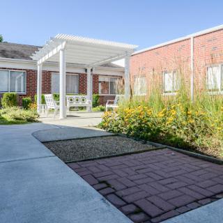 A serene garden pathway leading to a cozy outdoor seating area.