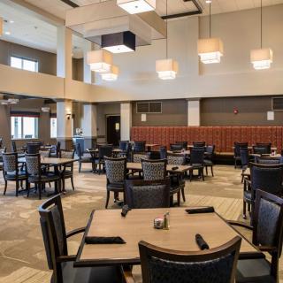 A modern restaurant interior featuring neatly arranged tables and chairs, with stylish lighting fixtures.