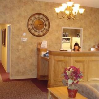 A welcoming reception area with a wooden desk, decorative clock, and flowers.