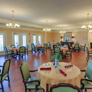 A spacious and elegantly furnished dining room with multiple round tables set with tablecloths.